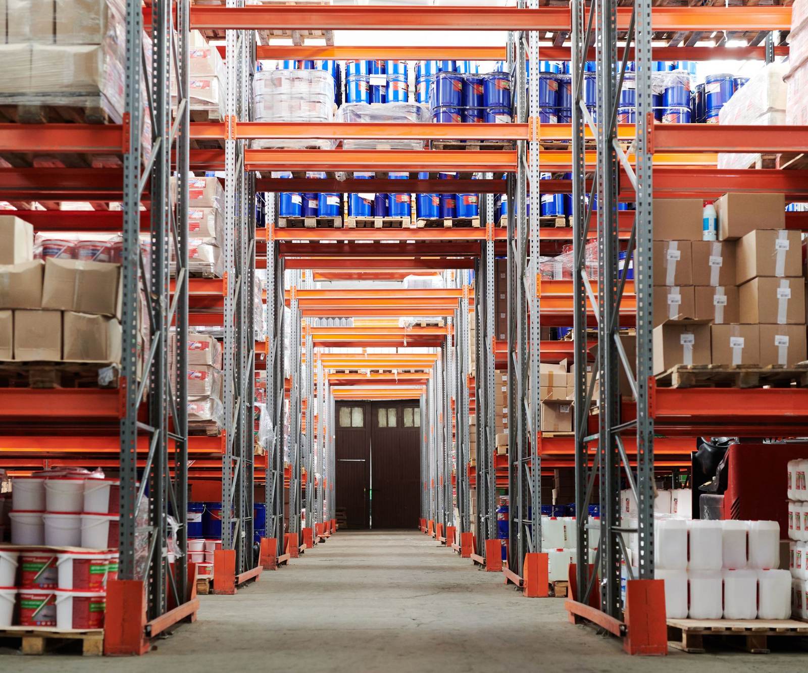 A distribution warehouse aisle with orange pallet racks stacked with boxes and drums, with stock, portal and dispatch cards from Odoo floating above