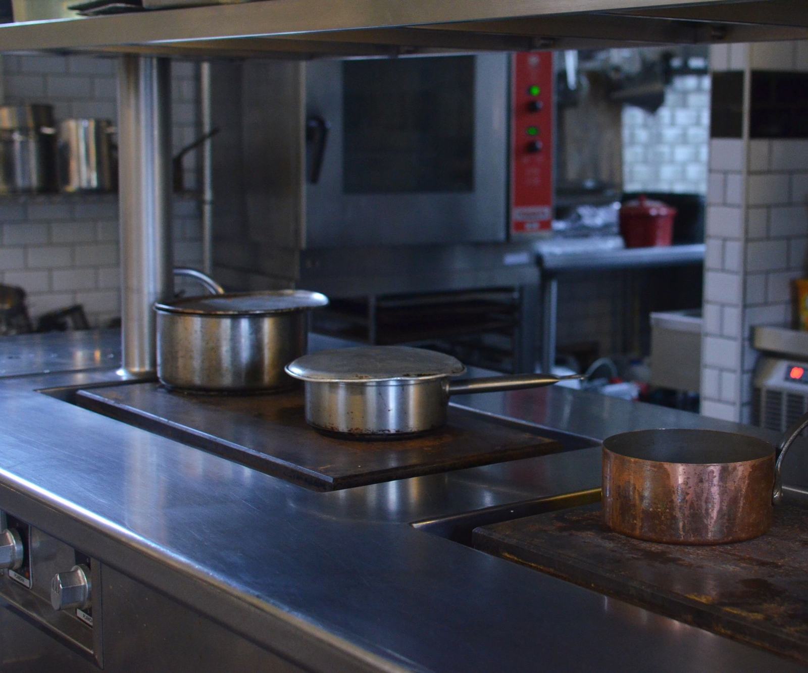 A stainless-steel production kitchen with pots on the cooking line, with order, kitchen and delivery cards from Odoo floating above